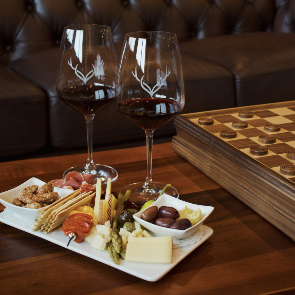 Photo of a display of charcuterie bites and two red wine glasses